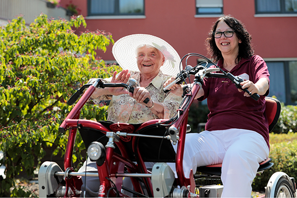 Seniorin und Mitarbeiterin auf dem Therapiefahrrad