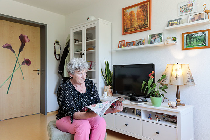 Eine Seniorin sitzt in ihrem Heimzimmer